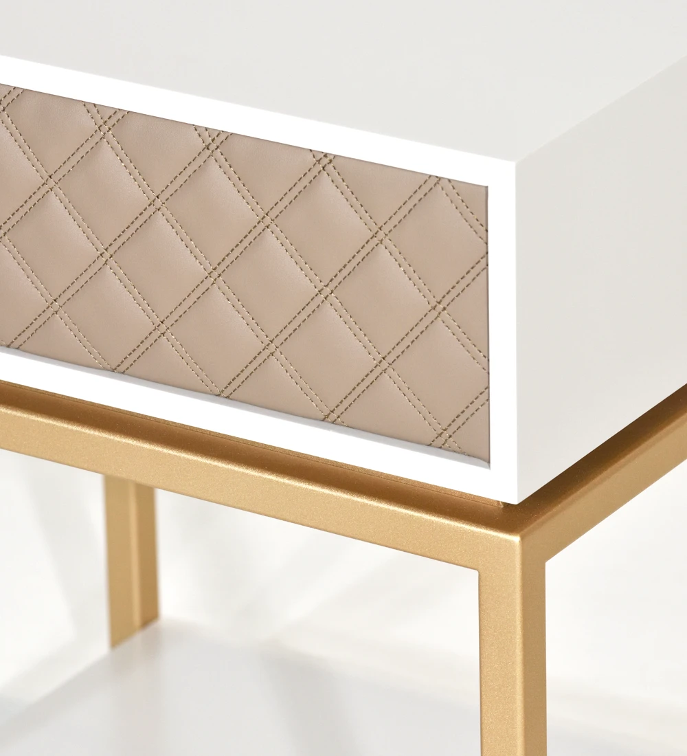 Table de chevet à 1 tiroir avec façade tapissée en tissu, structure laquée perle, avec pied en métal laqué or.