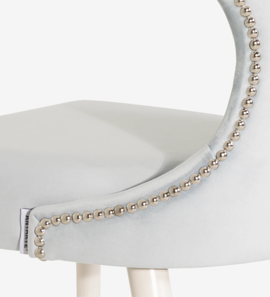 Chaise recouverte de tissu, avec un dossier argenté et des pieds laqués perle.