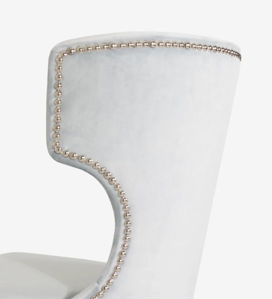Silla tapizada en tejido, con rebozado plateado en el respaldo y pies lacados en perla.