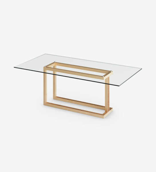 Mesa de comedor rectangular con tapa de cristal y pie de metal lacado en oro.