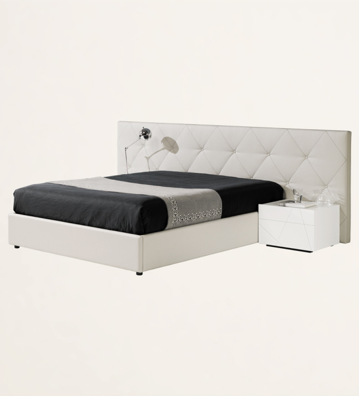 Cama de casal com cabeceira longa, estofada a ecopele branca, com arrumação através de estrado elevatório.