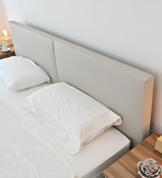 Double bed with headboard and footboard upholstered in light grey eco-leather, walnut sides.