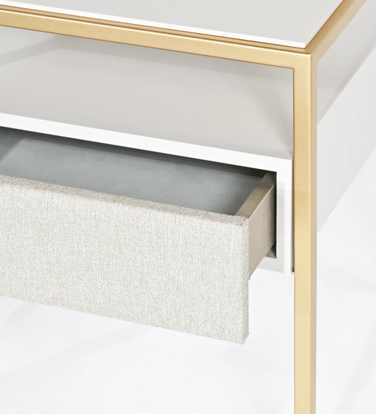 Table de chevet à 1 tiroir avec façade tapissée en tissu, plateau et module de tiroir laqués en perle, pied en métal laqué en or.